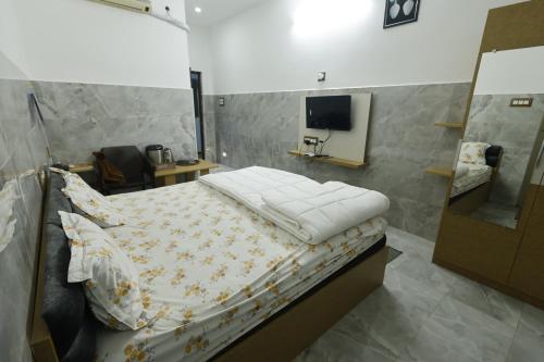 a bedroom with a bed and a tv on the wall at Sri Kalki Jamjam Resort in Erode