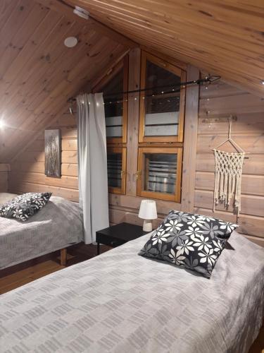 a bedroom with two beds and wooden walls at Latvahonka Cottage in Jämsä