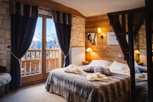a bedroom with a bed and a large window at Hôtel Chalet Alpage in La Clusaz