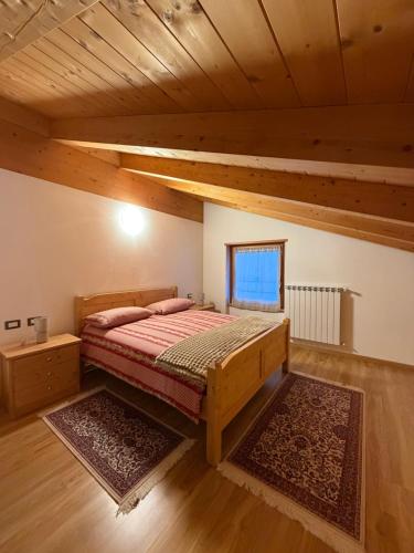 a bedroom with a bed in a room with wooden ceilings at Ca' de Mario in Sondalo