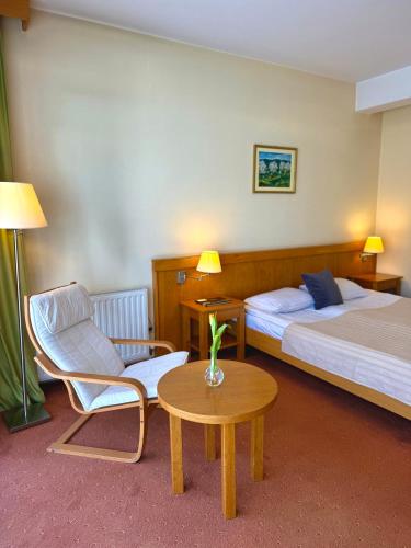a hotel room with two beds and a chair and a table at Hotel - Restaurant Gonduzo in Odorheiu Secuiesc
