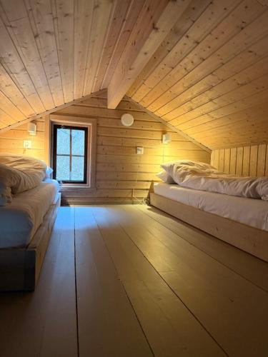 a room with two beds in a wooden cabin at Gjørven Hytter in Flåm