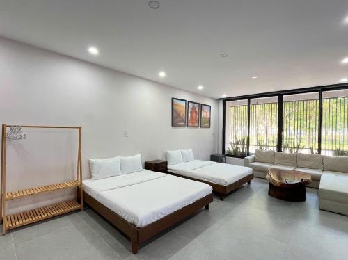 a room with two beds and a couch in it at Ranglux Homestay Phan Rang in Phan Rang–Tháp Chàm