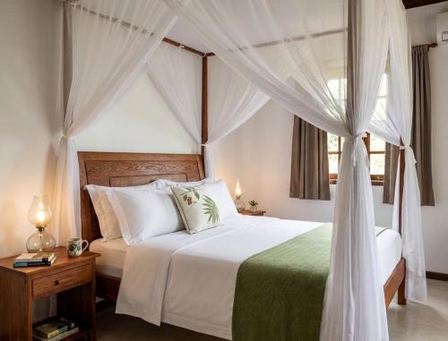 a bedroom with a white bed with a canopy at AZORAI - Hotel Boutique in Santa Cruz Cabrália