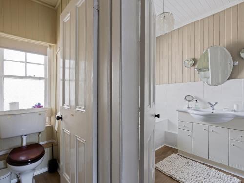ein Badezimmer mit Toilette, Waschbecken und Spiegel in der Unterkunft Ards House in Oban
