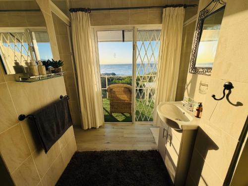 a bathroom with a sink and a view of the ocean at La Melamire On the Rocks Bed & Breakfast in Gansbaai