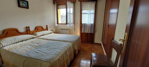 a bedroom with a bed and a window and a door at APARTAMENTOS RURALES PERNÚS in Colunga