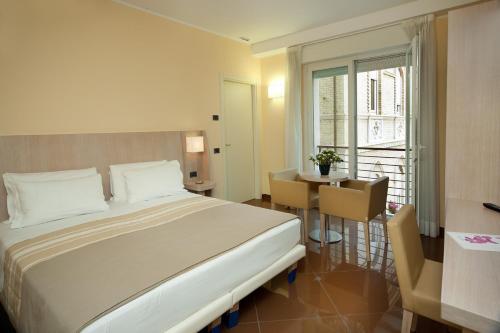 a bedroom with a bed and a table and a window at Hotel Chiaraluna in Civitanova Marche