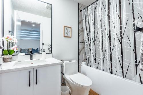 a bathroom with a toilet and a shower curtain at Executive Basement suite in Edmonton