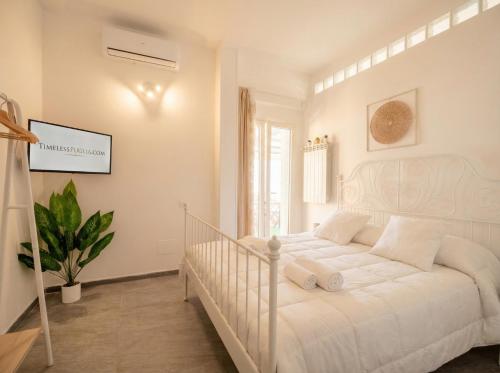 a white bedroom with a white bed and a plant at CarmenLeo-Central Accommodation with Patio in Polignano a Mare