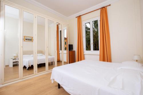 a white bedroom with a bed and a mirror at Grand Hotel De Londres in Sanremo