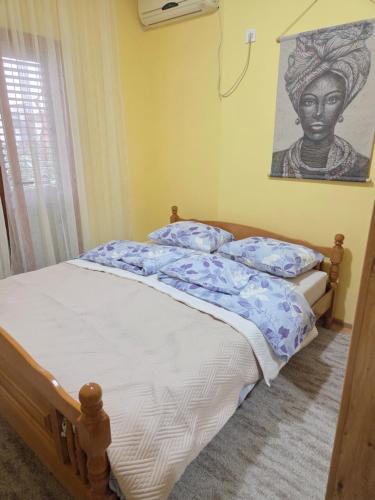 a bedroom with a bed with a painting on the wall at Cosy Apartment in Podgorica - Fast WiFi & cable TV in Konik