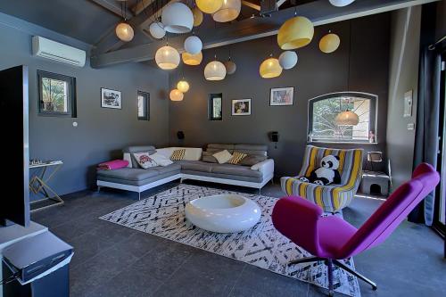 a living room with a couch and pink chairs at Villa d'Exception 330m Piscine 12x6 in Fontaines-Saint-Martin