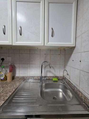 a stainless steel sink in a kitchen with white cabinets at Ajman Studio Downtown B2OO7 in Ajman 