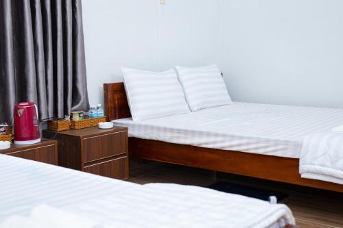 a bedroom with two beds with white sheets and a window at Khách sạn Cozy Home 2 in Can Tho