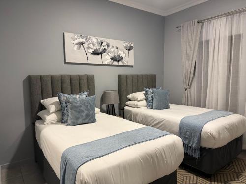 two beds in a room with white and blue at Belo Villa Clarens in Clarens
