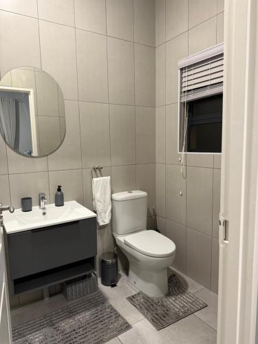 a bathroom with a toilet and a sink and a mirror at Belo Villa Clarens in Clarens