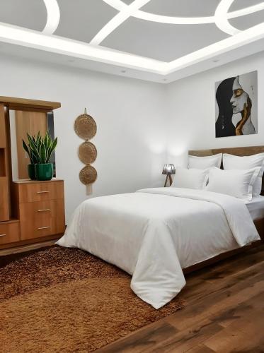 a white bedroom with a large white bed with white sheets at pyramids view luxury apartment in ‘Ezbet `Abd el-Ḥamîd