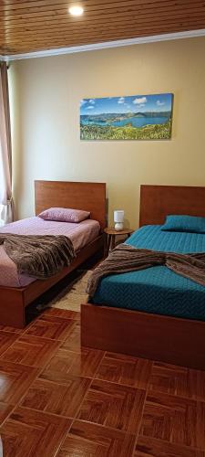 two beds in a room with wooden floors at Casa do Faial da Terra in Faial da Terra