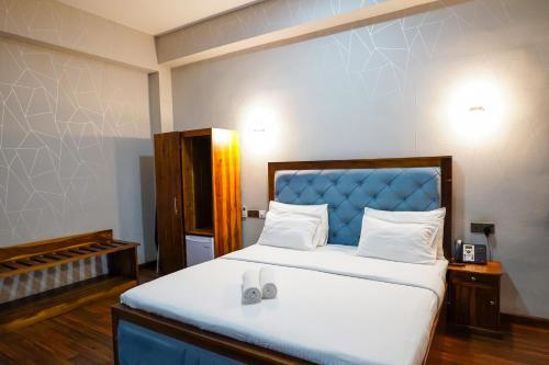 a bedroom with a large bed with a blue headboard at CROWN REGENCY- BADULLA in Badulla
