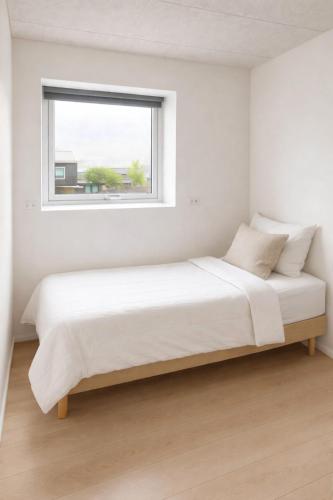 a bed in a white room with a window at Rogvi's new appartment in Klaksvík