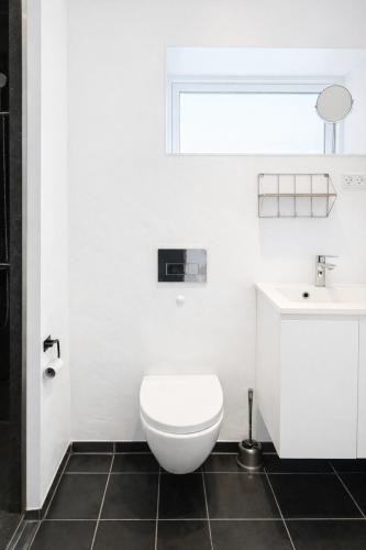 a white bathroom with a toilet and a sink at Rogvi's new appartment in Klaksvík