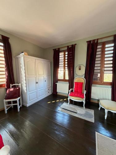 a living room with a red chair and some windows at La Gloriette Riquewihr in Riquewihr