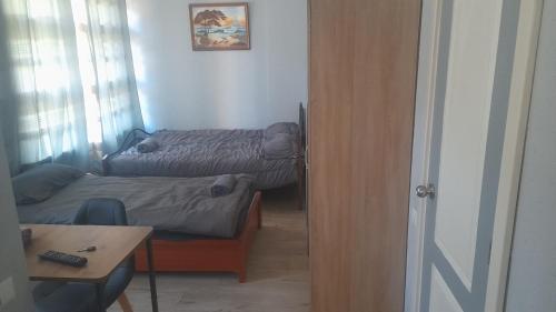 a room with two beds and a desk and a table at Apartment Vecliepaja in Liepāja