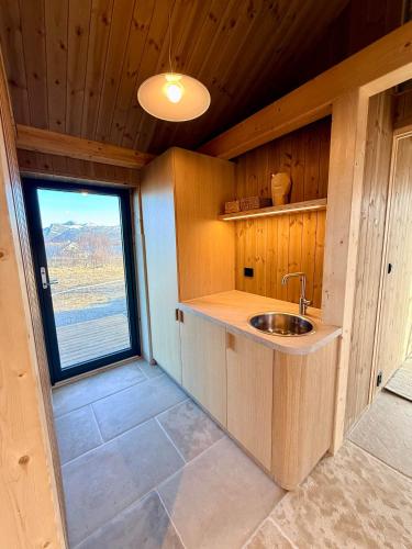 a kitchen with a sink and a window in a cabin at Storøya Lodge Lofoten in Vestvågøya