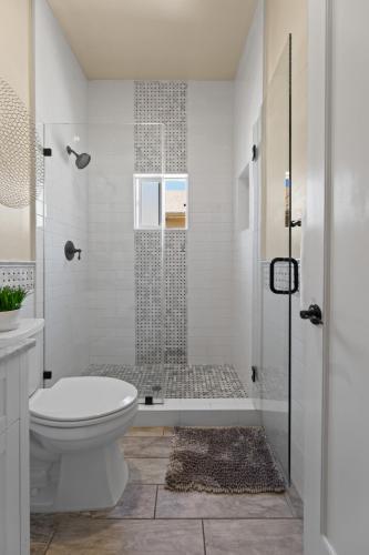 a white bathroom with a shower and a toilet at Upscale 1890s Historic Apartment in Sacramento
