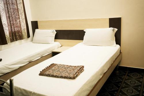 two beds in a room with white sheets and a pillow at Hotel BMR Stay in Pollāchi