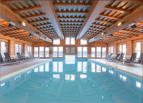 a large swimming pool with chairs in a building at 4009 loft penthouse Prince des Cimes Arc 1950 in Arc 1950