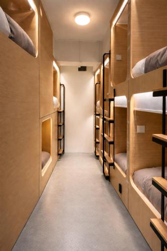 a row of bunk beds in a room with a hallway at Wink at Jalan Besar in Singapore