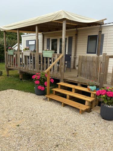 a house with a deck with a tent and flowers at Bungalow 6 personnes in Équihen-Plage