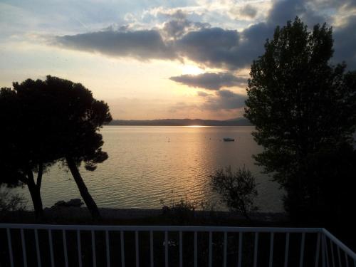 a sunset over a body of water with trees at Hotel Saviola in Sirmione