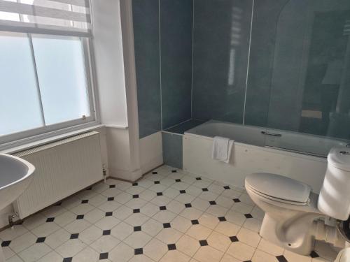 a bathroom with a toilet and a tub and a sink at The Havelock in Nairn