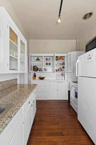 a white kitchen with white appliances and wooden floors at Historic Charm with Parking in Center of Midtown in Sacramento