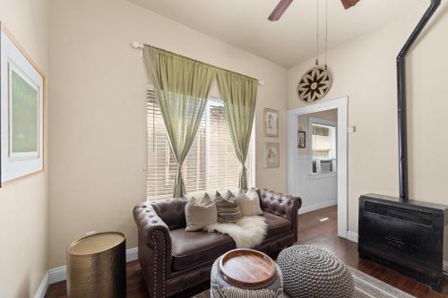 a living room with a leather couch in front of a window at Historic Charm with Parking in Center of Midtown in Sacramento
