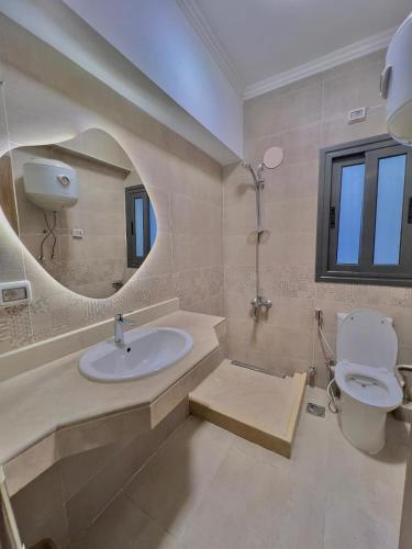 a bathroom with a sink and a toilet and a mirror at دقيقه للبحيره أقامه فندقيه مدينتي بريفادو madinaty privado in Madinaty