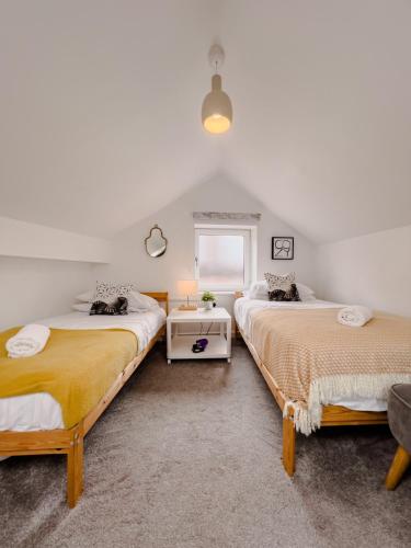two beds in a room with a window at Stylish Loft in Stockport - Free Parking - 10 min to Manchester - Flat 1 in Stockport