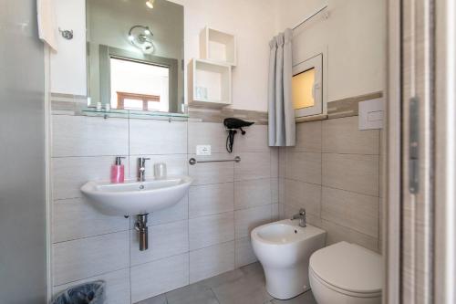 a white bathroom with a sink and a toilet at Il Torrazzo da Francesca in San Vito lo Capo