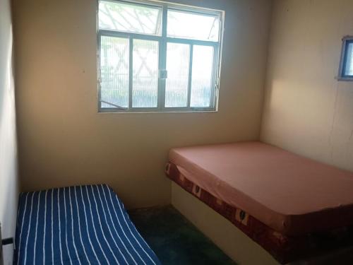 a small room with two beds and a window at Casa em Araruama com 3 quartos e muito arejada in Araruama