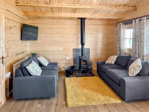 a living room with two couches and a fireplace at Wind Hall Log Cabin in Gosforth