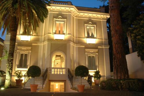 a large white building with stairs and palm trees at Hotel Flora in Frascati