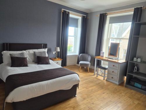 a bedroom with a bed and a desk with a television at The Havelock in Nairn