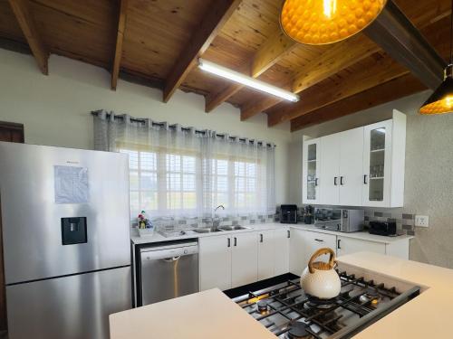 a kitchen with white cabinets and a stainless steel refrigerator at Vaal Dam Getaway in Denysville