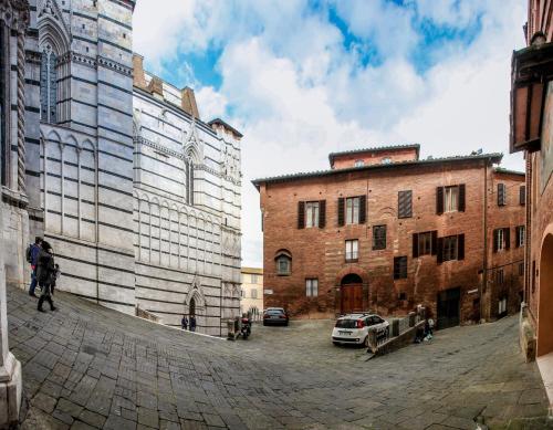a man walking down a street next to a brick building at Palazzo del Magnifico B&B in Siena