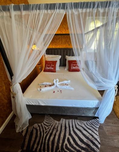 a bed in a room with curtains and a zebra print rug at Ô Balcon in Sainte-Rose