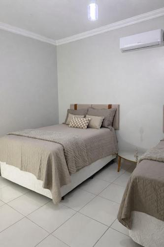 a white bedroom with a bed and a white tile floor at CS2 - Ampla - Suítes e Ar-Cond em Todos os Quartos in Juazeiro do Norte