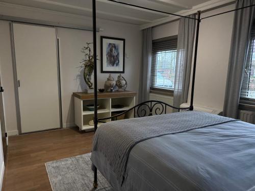 a bedroom with a bed and a table and windows at Villa France in Sevenum